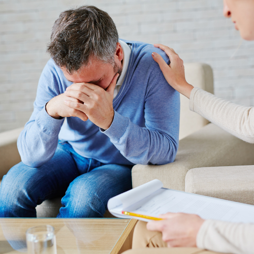 man hunched over being comforted