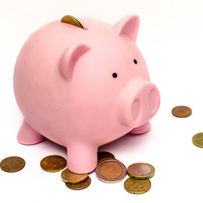 pink piggy bank with coins around it