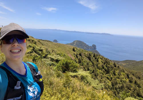 Marathon runner stood on a mountain with a view of the sea
