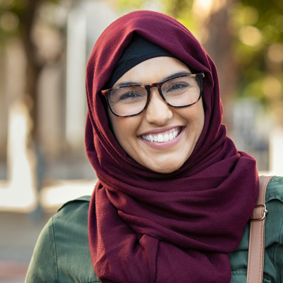 woman in red hijab and glasses smiling at camera