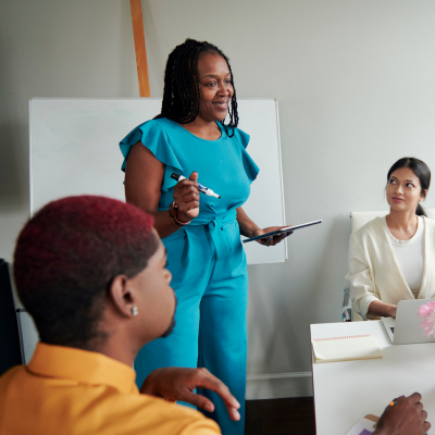 Woman in bright blue jumpsuit talking to team