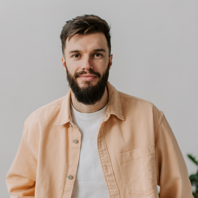 Man with beard in orange shirt looking straight at camera