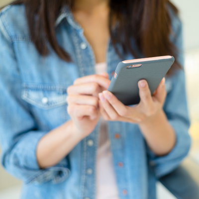 woman in blue shirt looking at mobile phone